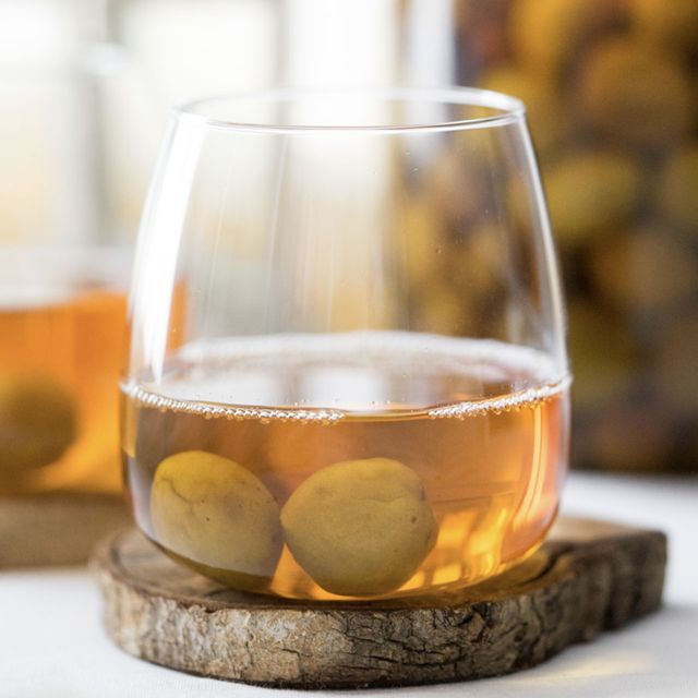 Mountain plum and tea liqueur with whole plums in an amber glass